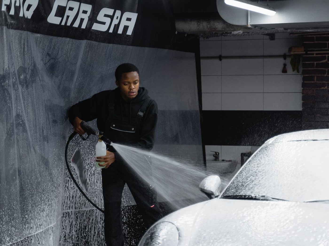 Detailer applying protective foam in a car spa bay
